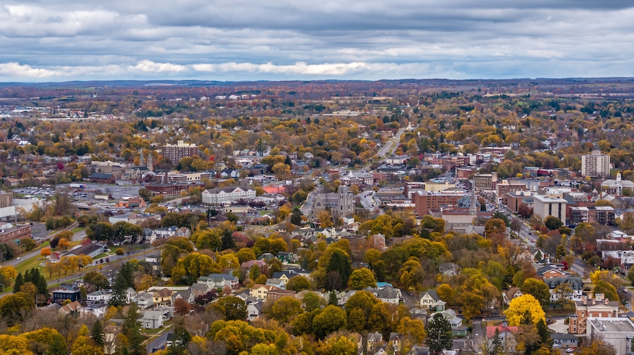 A cityscape with autumn foliage, a prominent church, and a distant mountain range.