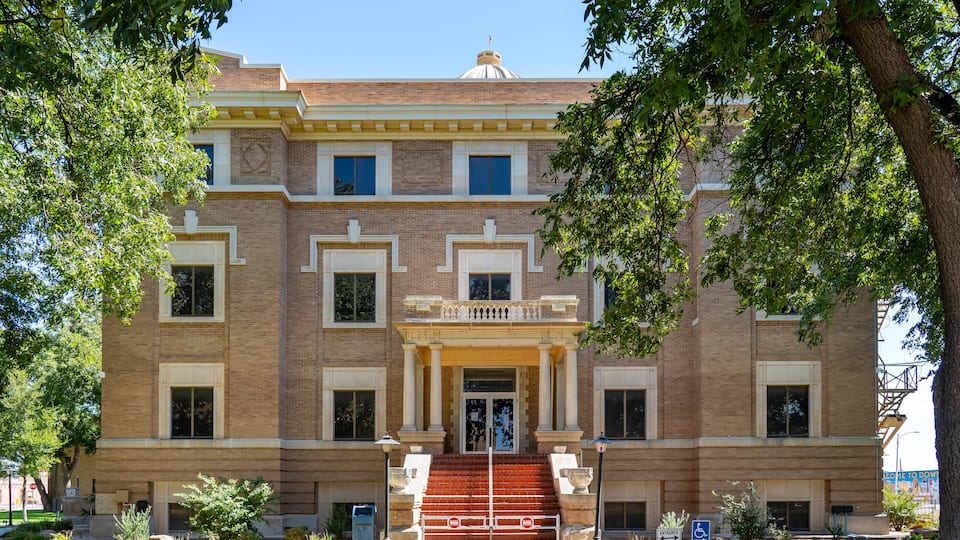 A historic building with a central entrance, large windows, and a brick facade.