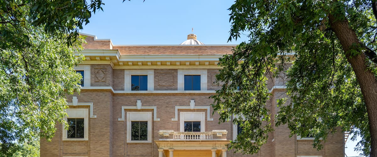 A historic building with a central entrance, large windows, and a brick facade.