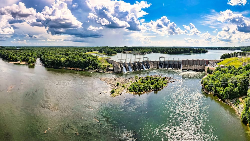 An aerial 180 degree panoramic view of a large dam and hydroelectric plant on the Catawba river in South Carolina and Lake Wylie in the background.