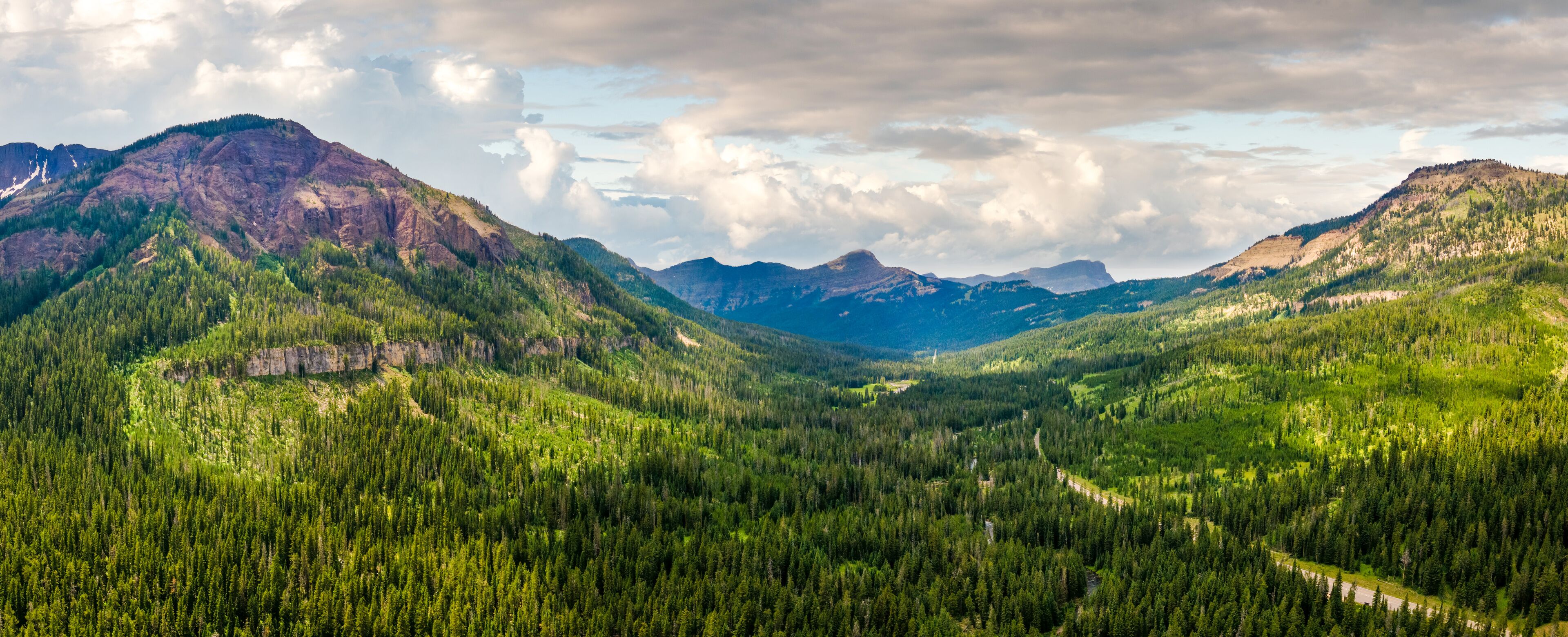 A mountainous landscape with dense forests and a winding road.