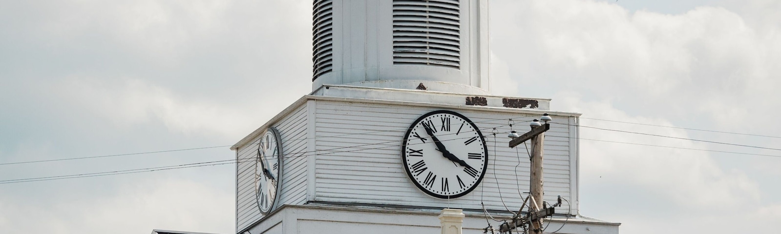 A clock tower with a gold dome and an American flag, set against a cloudy sky.