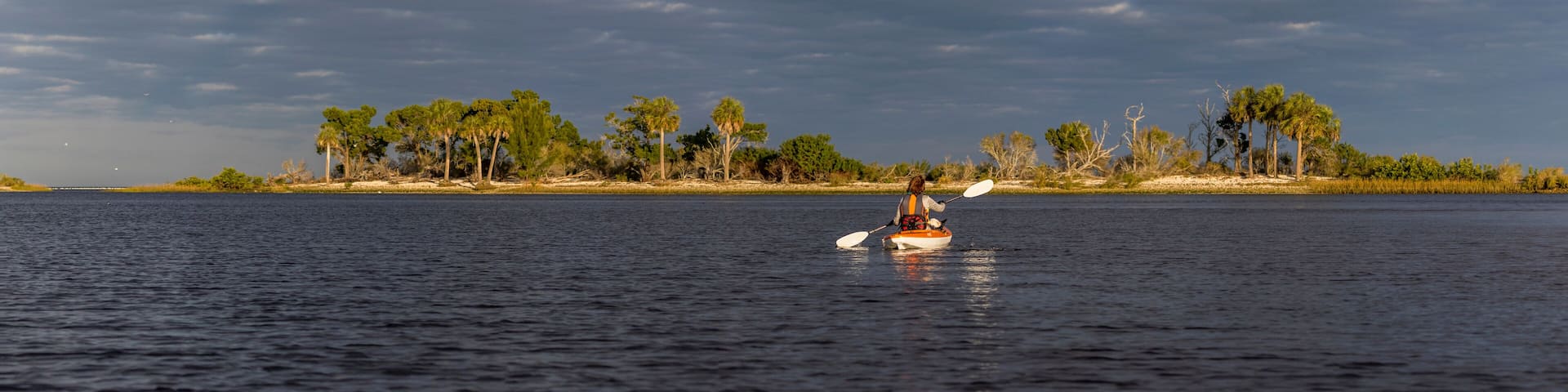 Panorama of woman kayaking in the Gulf of Mexico with birds flying overhead