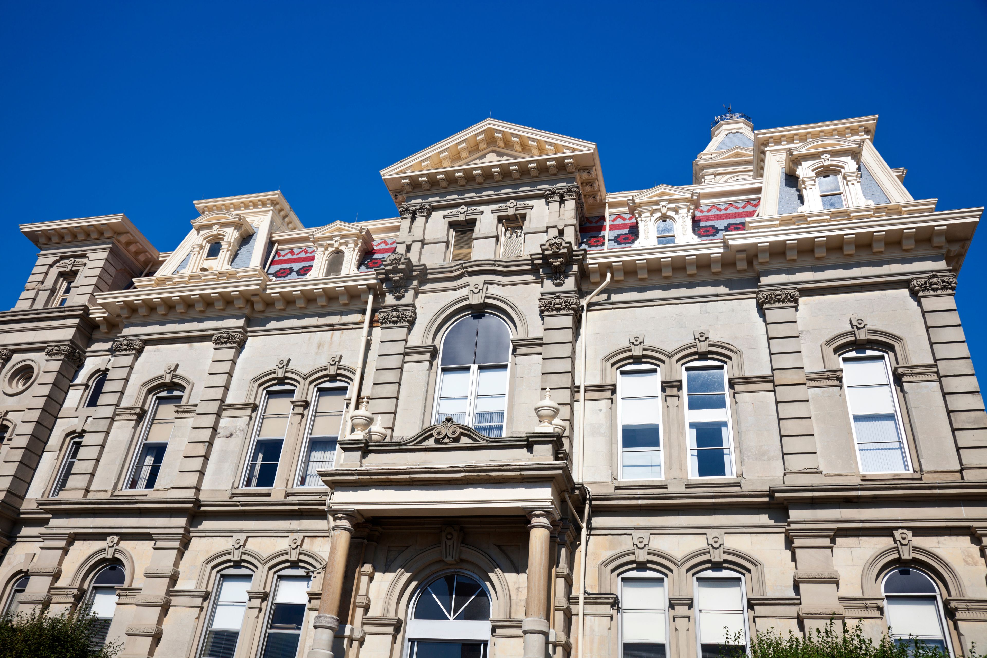 Un grand bâtiment imposant, orné de nombreuses fenêtres en arc et d’éléments décoratifs.