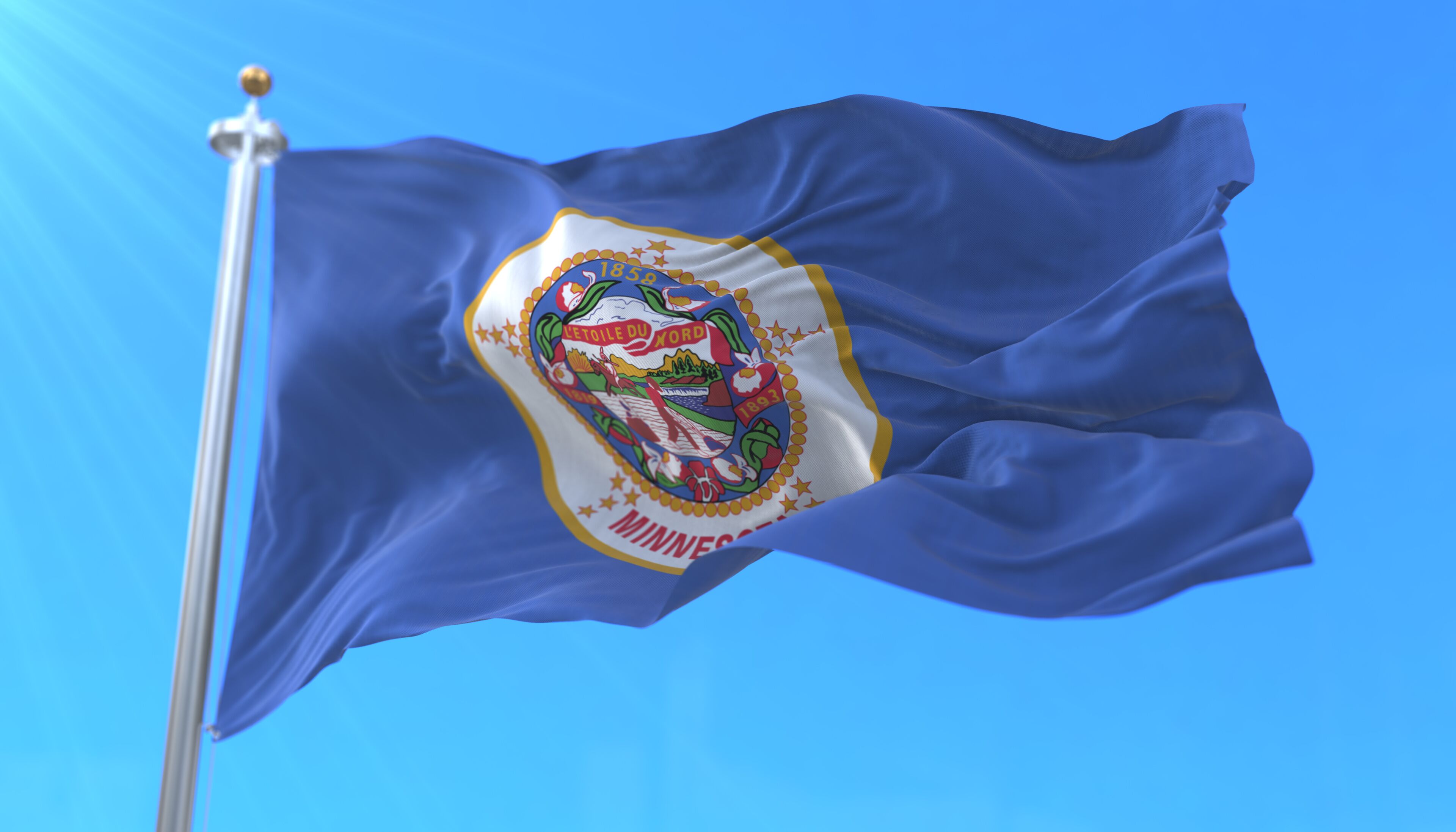 A flag with a detailed emblem and the year 1858, fluttering on a flagpole against a clear blue sky.
