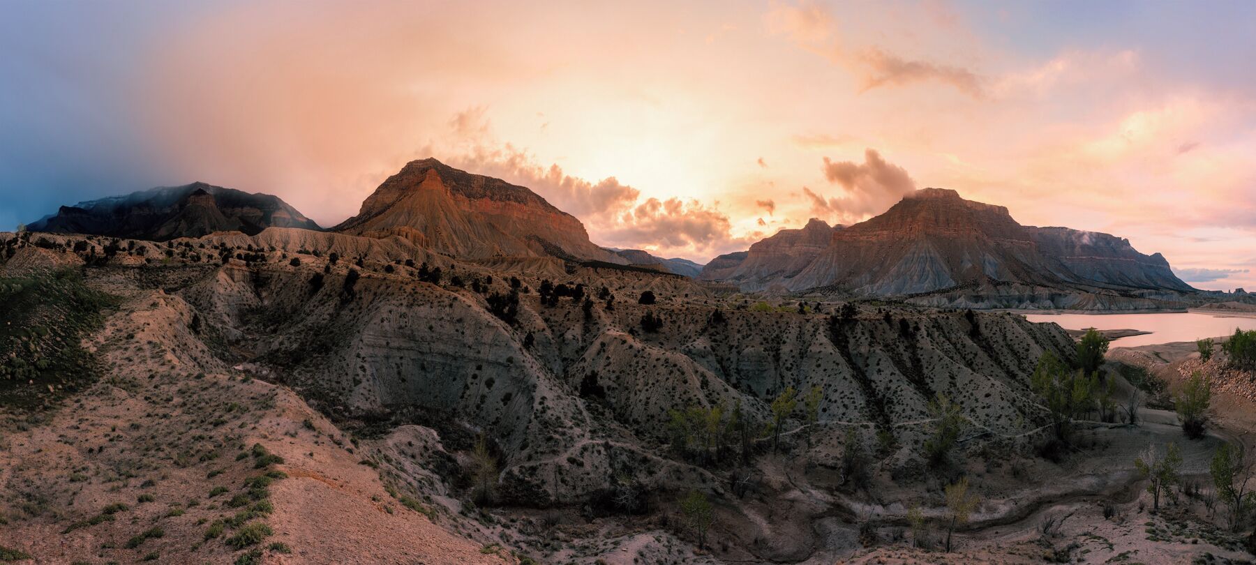 Un paisaje agreste con formaciones rocosas estratificadas y vegetación escasa.