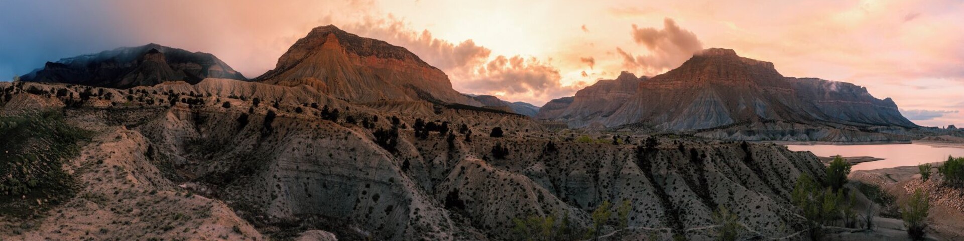 Un paisaje agreste con formaciones rocosas estratificadas y vegetación escasa.