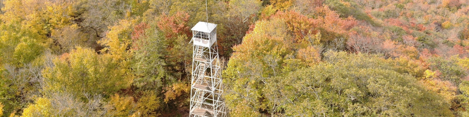 Aerial of Kane Mountain Fire Tower with autumn forest scape water near Fulton County, New York