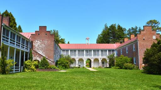 A historic building with a red roof, brick walls, and arched walkways.