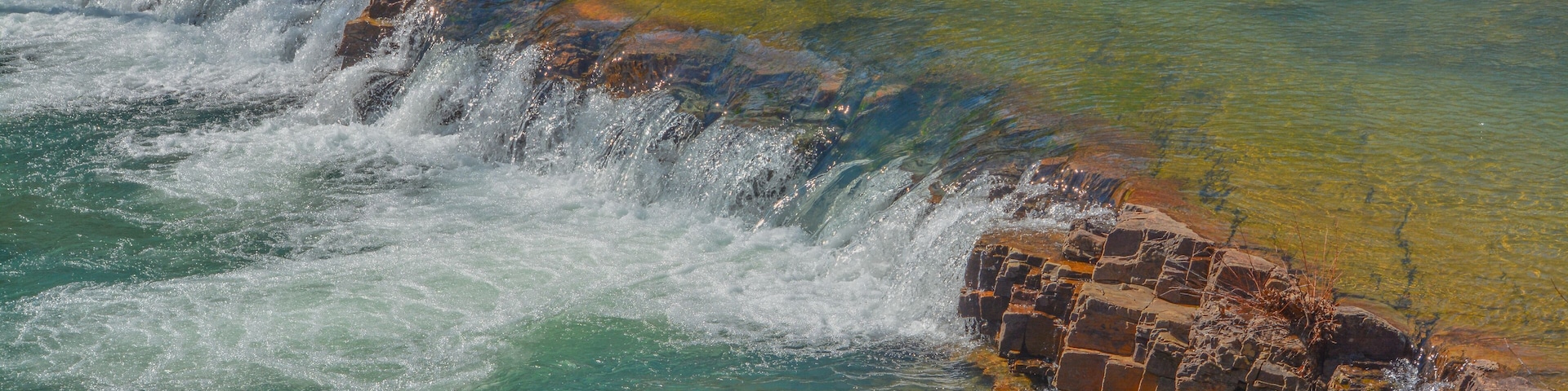 A waterfall cascading over rocks into clear, turquoise water.