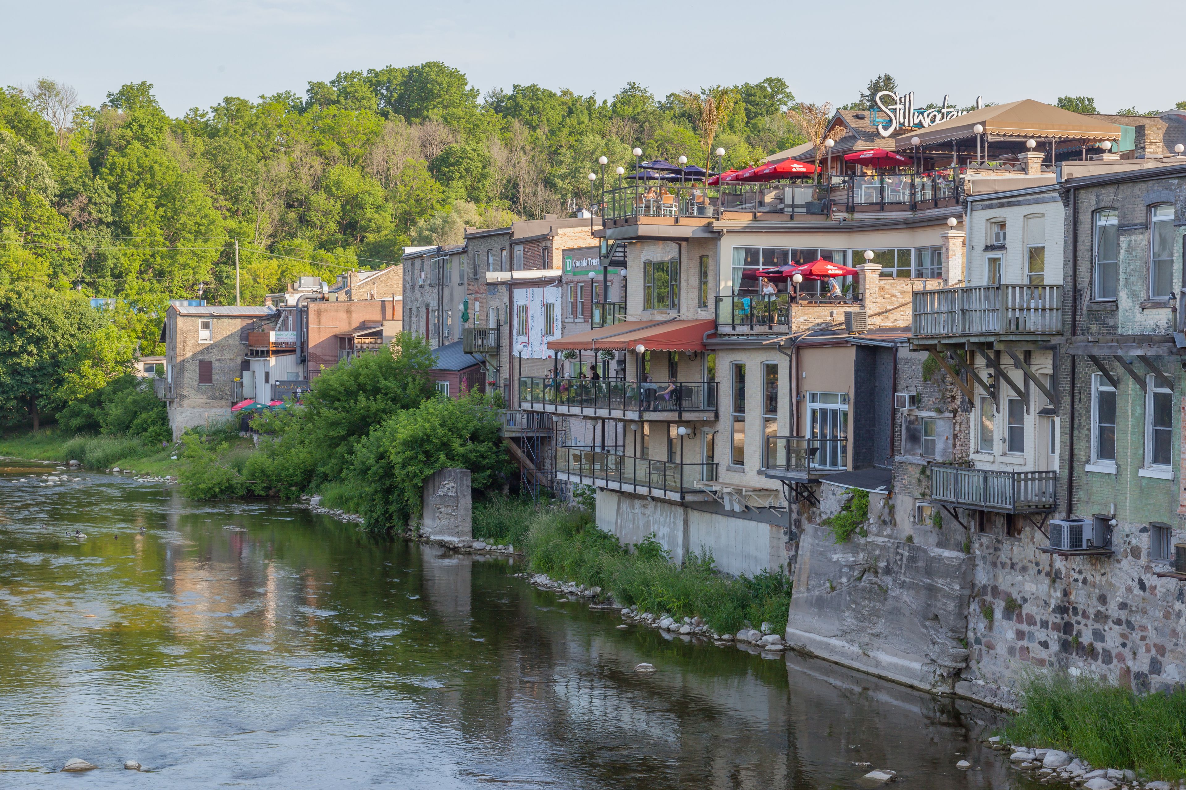 A river with buildings along its banks, a sign for 'Stillwater,' and a bridge.