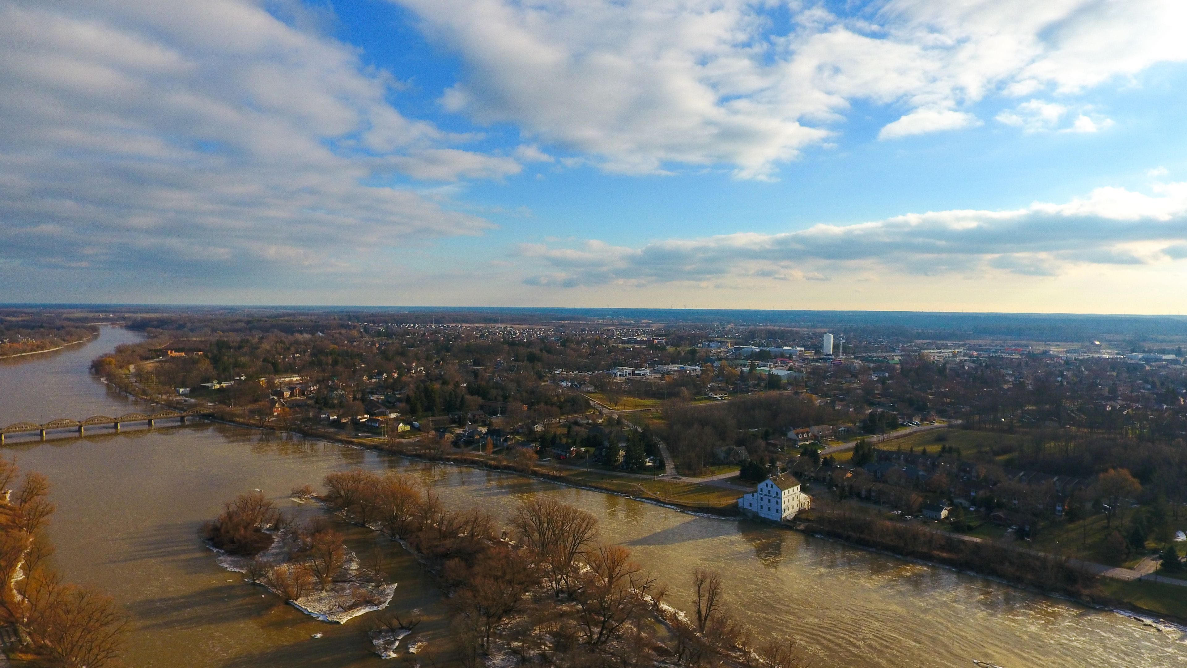 A river flowing through a town with a bridge, buildings, and trees.