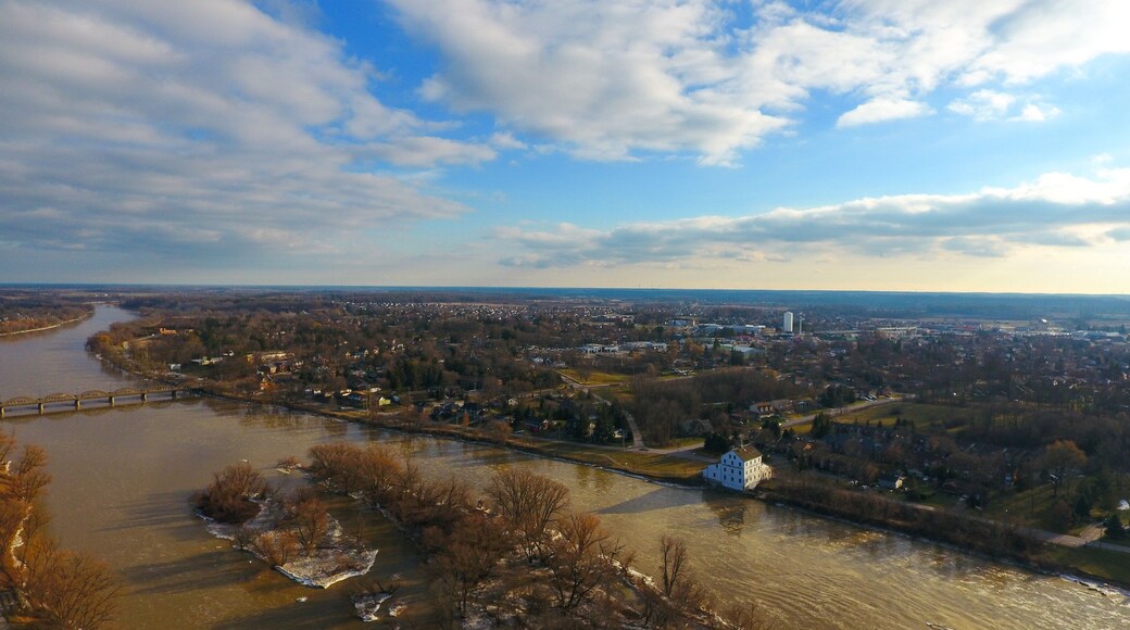 A river flowing through a town with a bridge, buildings, and trees.