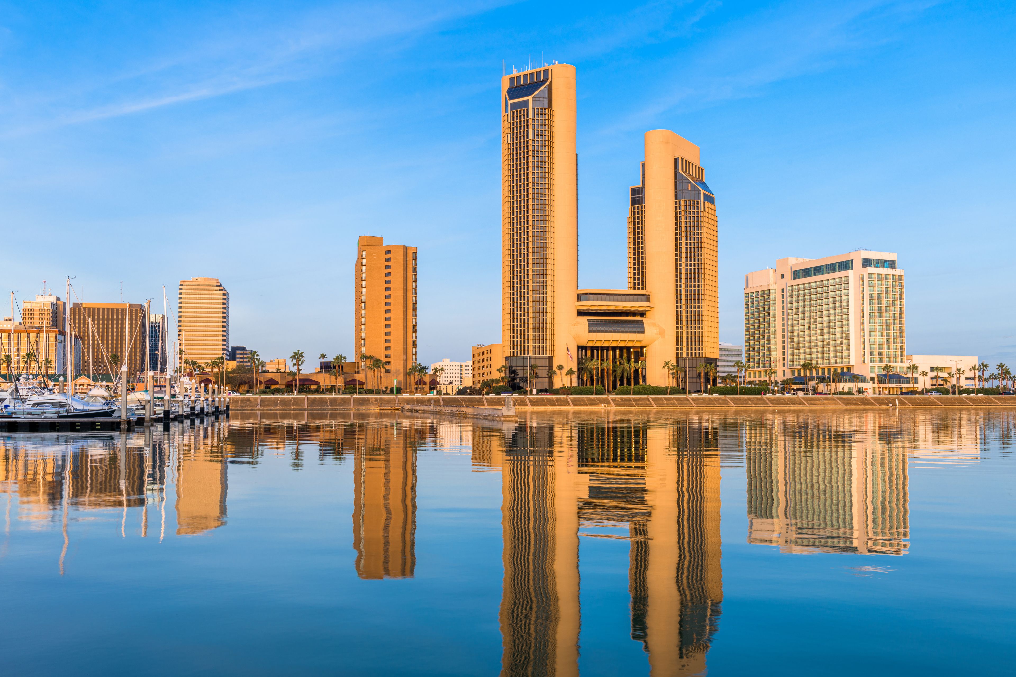 Un horizonte urbano con edificios altos reflejados en agua tranquila.