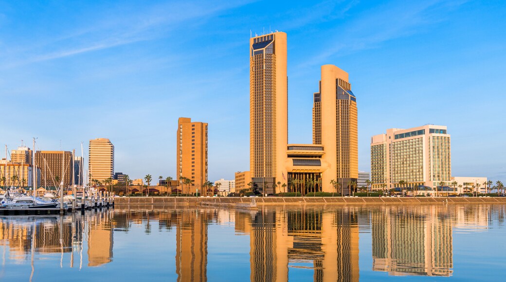 Un horizonte urbano con edificios altos reflejados en agua tranquila.