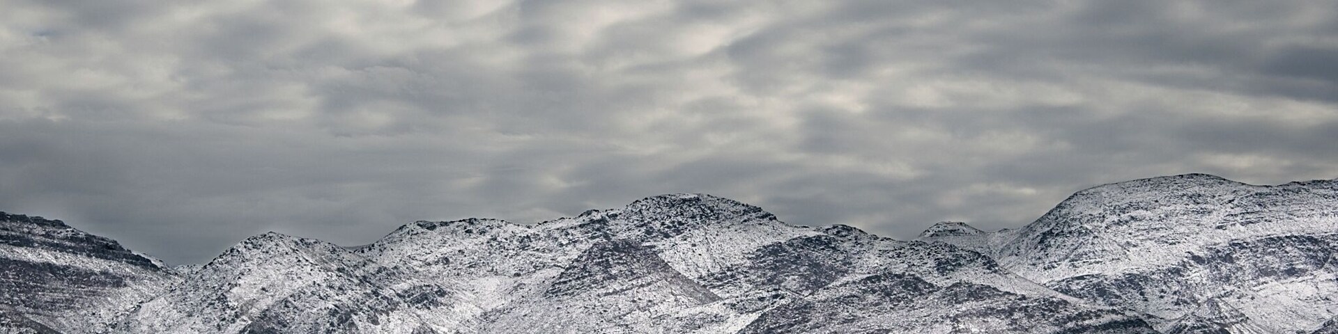 Una cordillera nevada con un primer plano seco y herboso.
