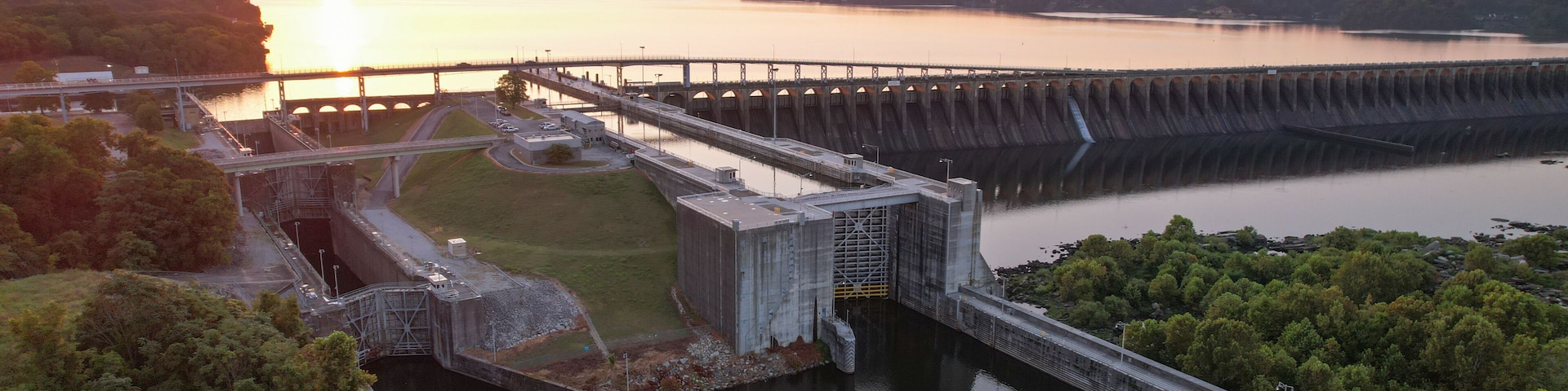 Un barrage surmontĂ© dâun pont, un rĂ©servoir et un coucher de soleil.