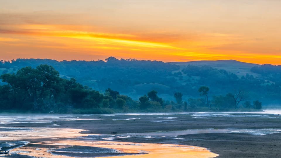 A river at sunset with hills in the background.