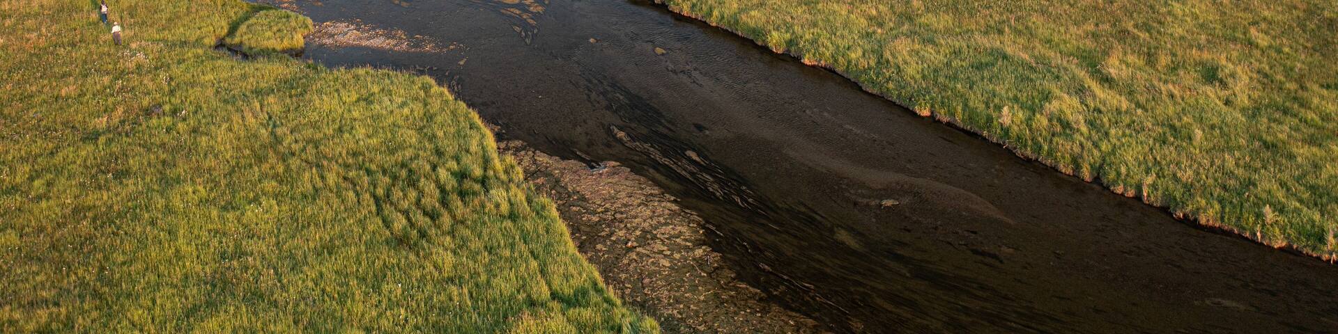 River winding through open field during late summer in Montana.