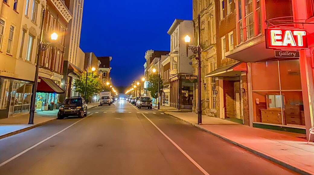 A street lined with historic buildings, a prominent red 'EAT' sign, and a clear night sky.