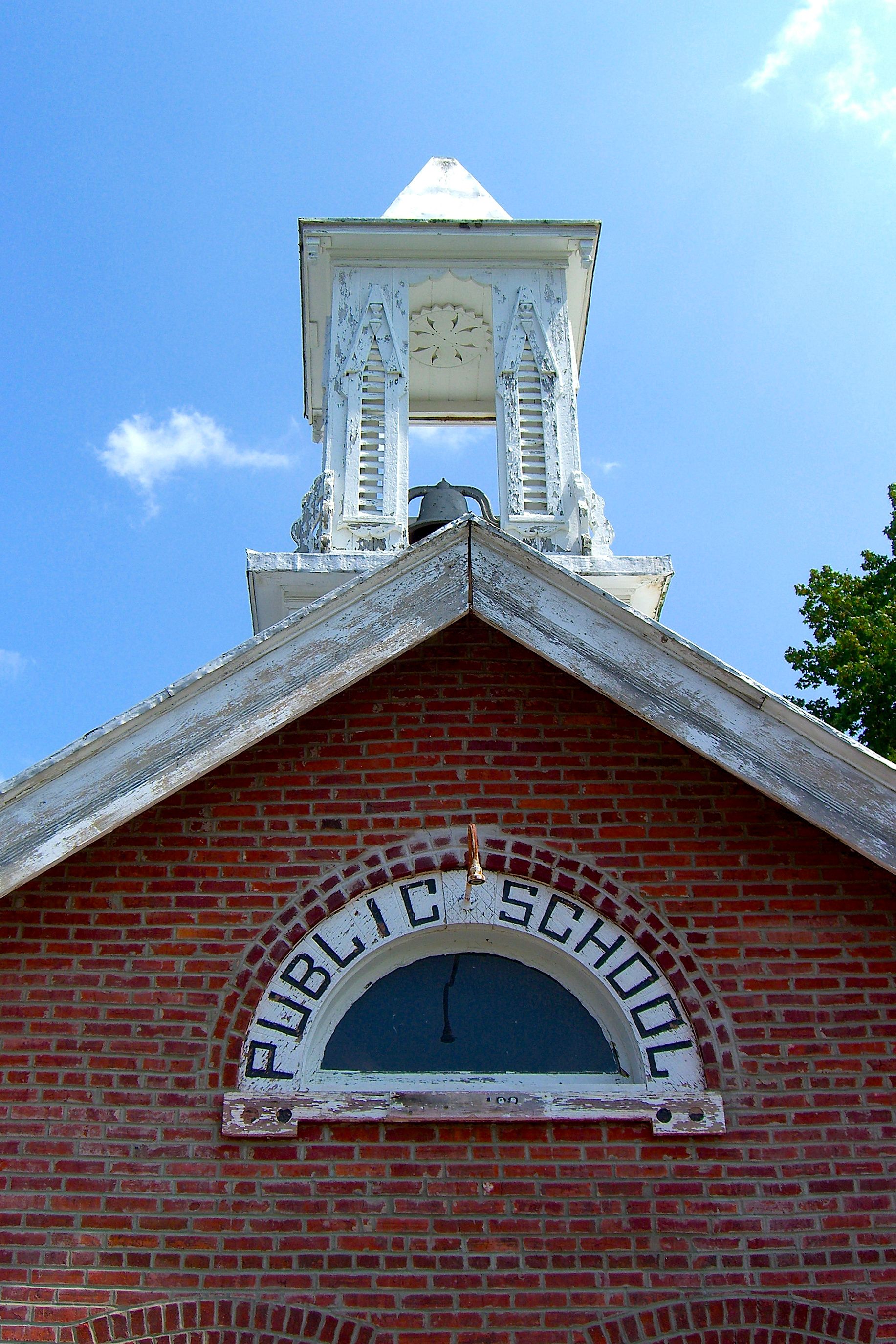 A brick building with a white steeple and a clock.