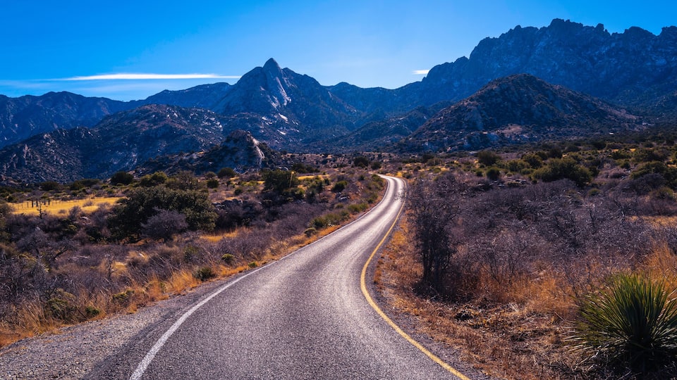 A winding road through a mountainous landscape with sparse vegetation and rocky terrain.