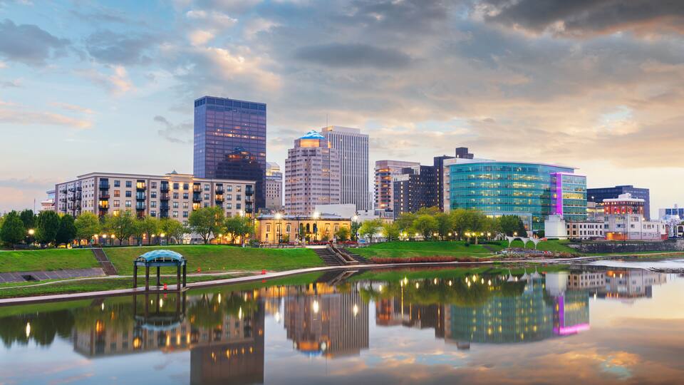 A city skyline with modern buildings and a calm river reflecting the structures.