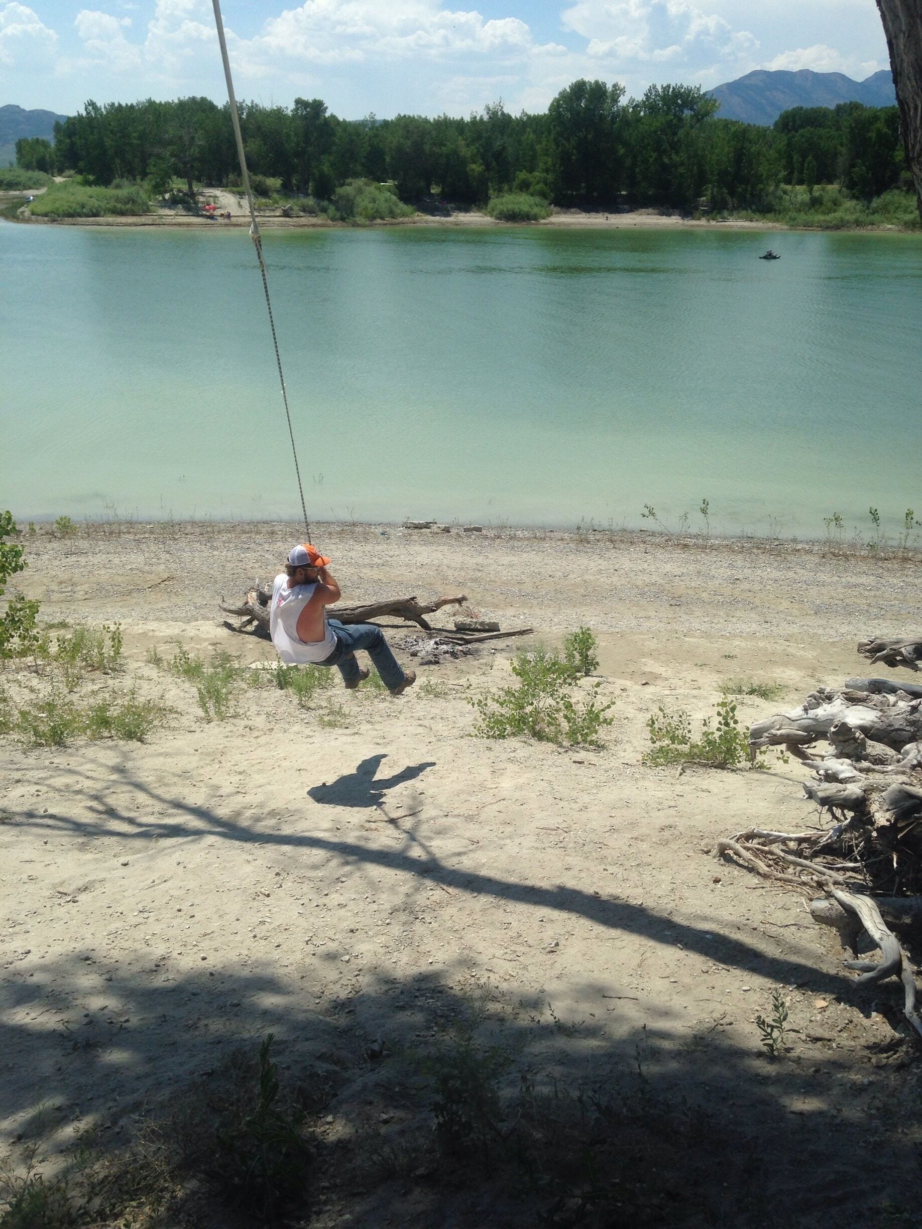 A person fishing by a calm lake with a clear sky.