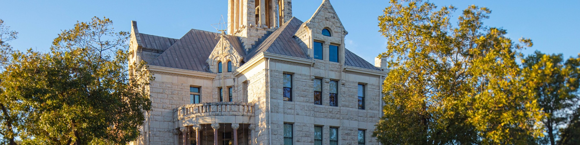 A historic stone building with a prominent tower and arched windows.