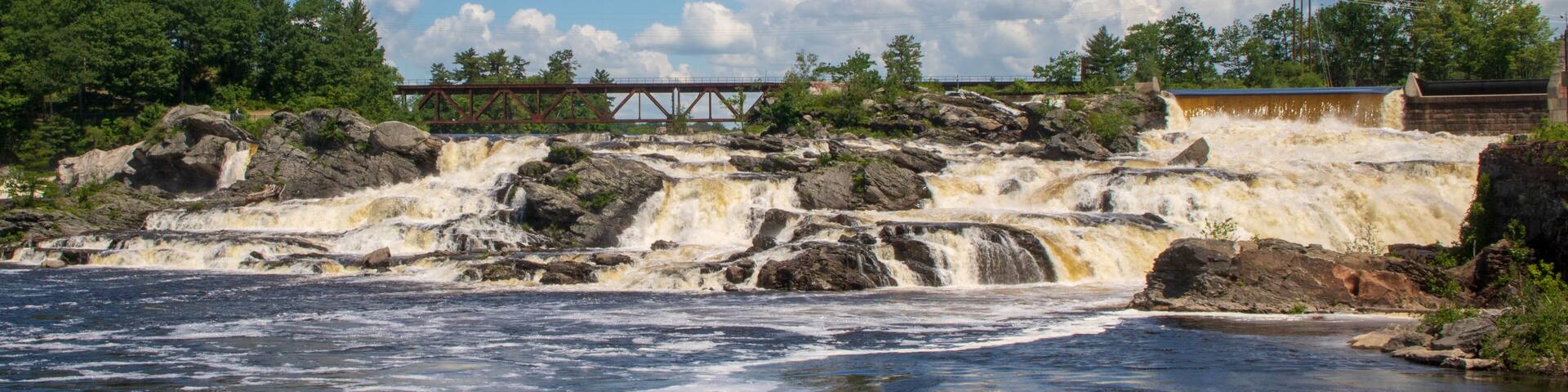 A river with a waterfall, a bridge, and a dam.
