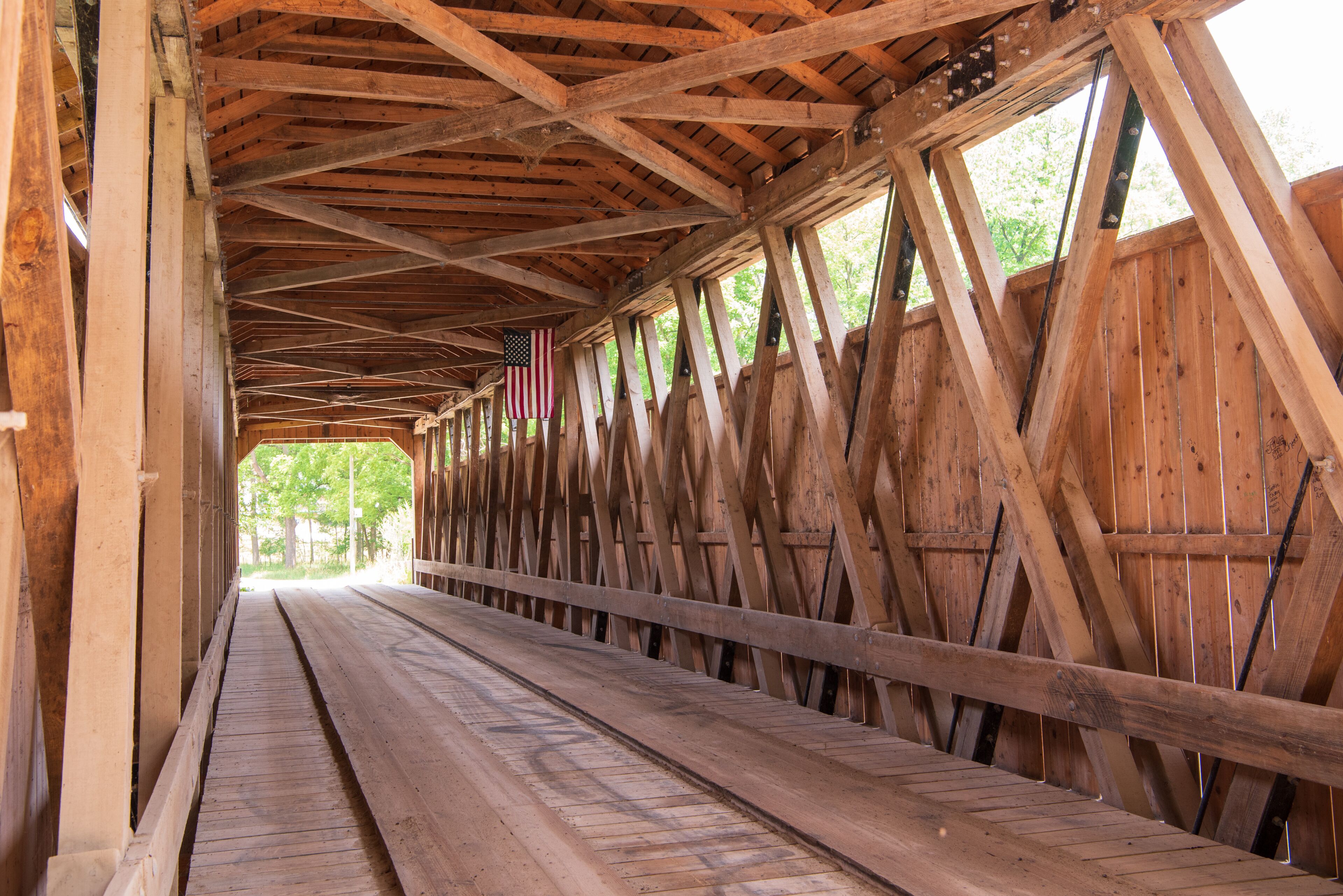 Un pont couvert en bois, doté d’un plancher en bois et d’une rambarde en métal.