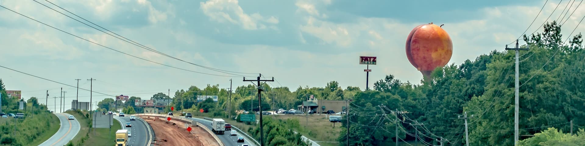 A highway with a roundabout, a construction site, and a large hot air balloon in the distance.