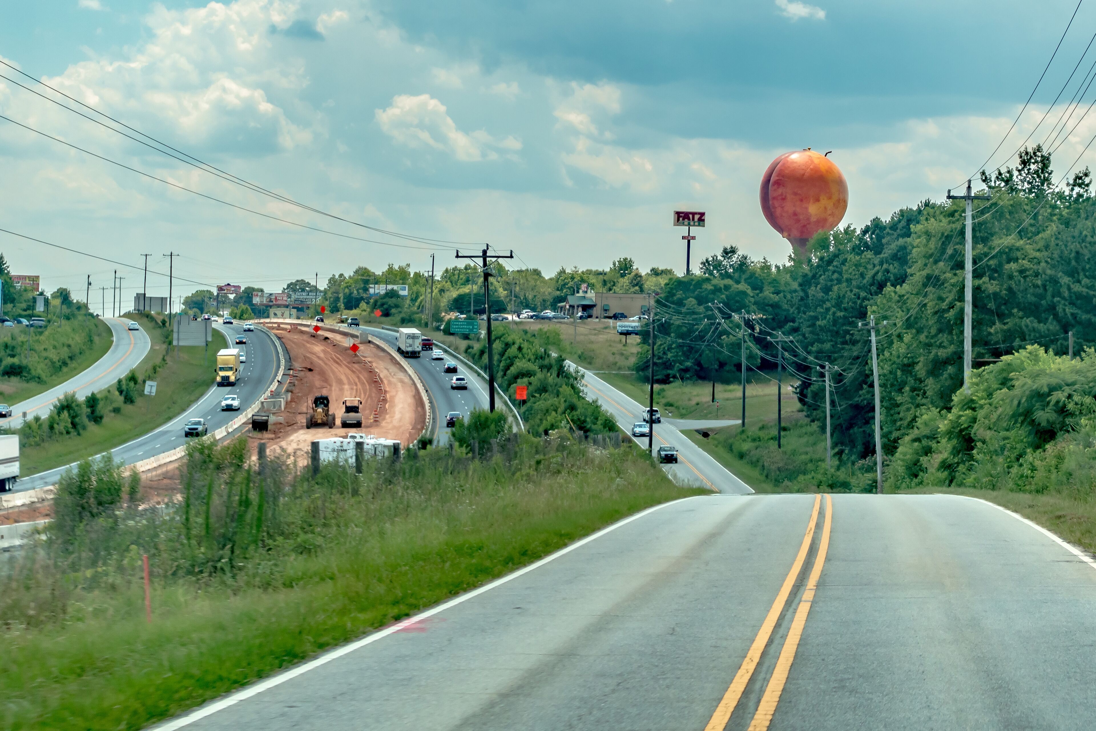 A highway with a roundabout, a construction site, and a large hot air balloon in the distance.