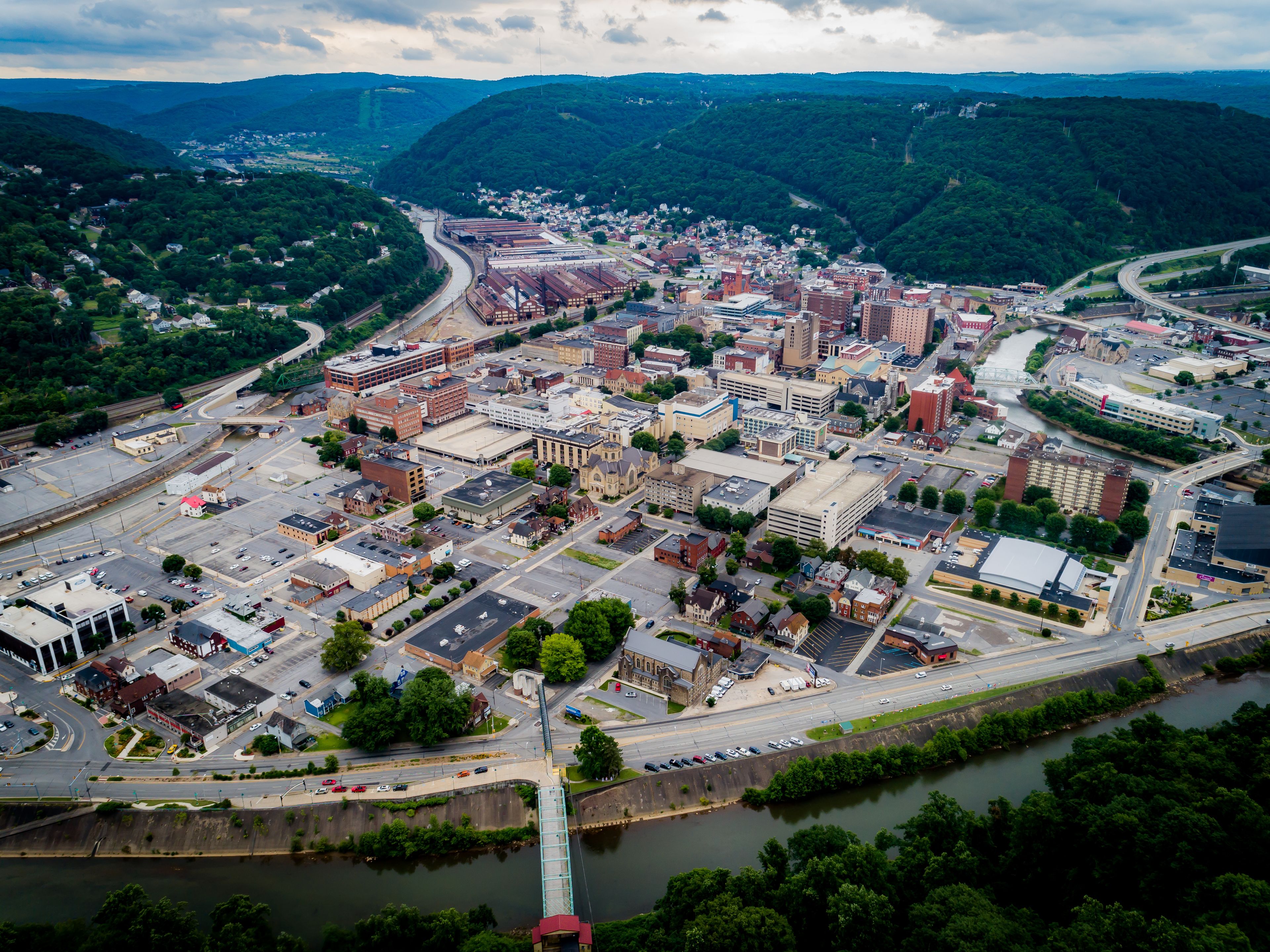 An aerial view of a city with a river, bridges, and surrounding hills.