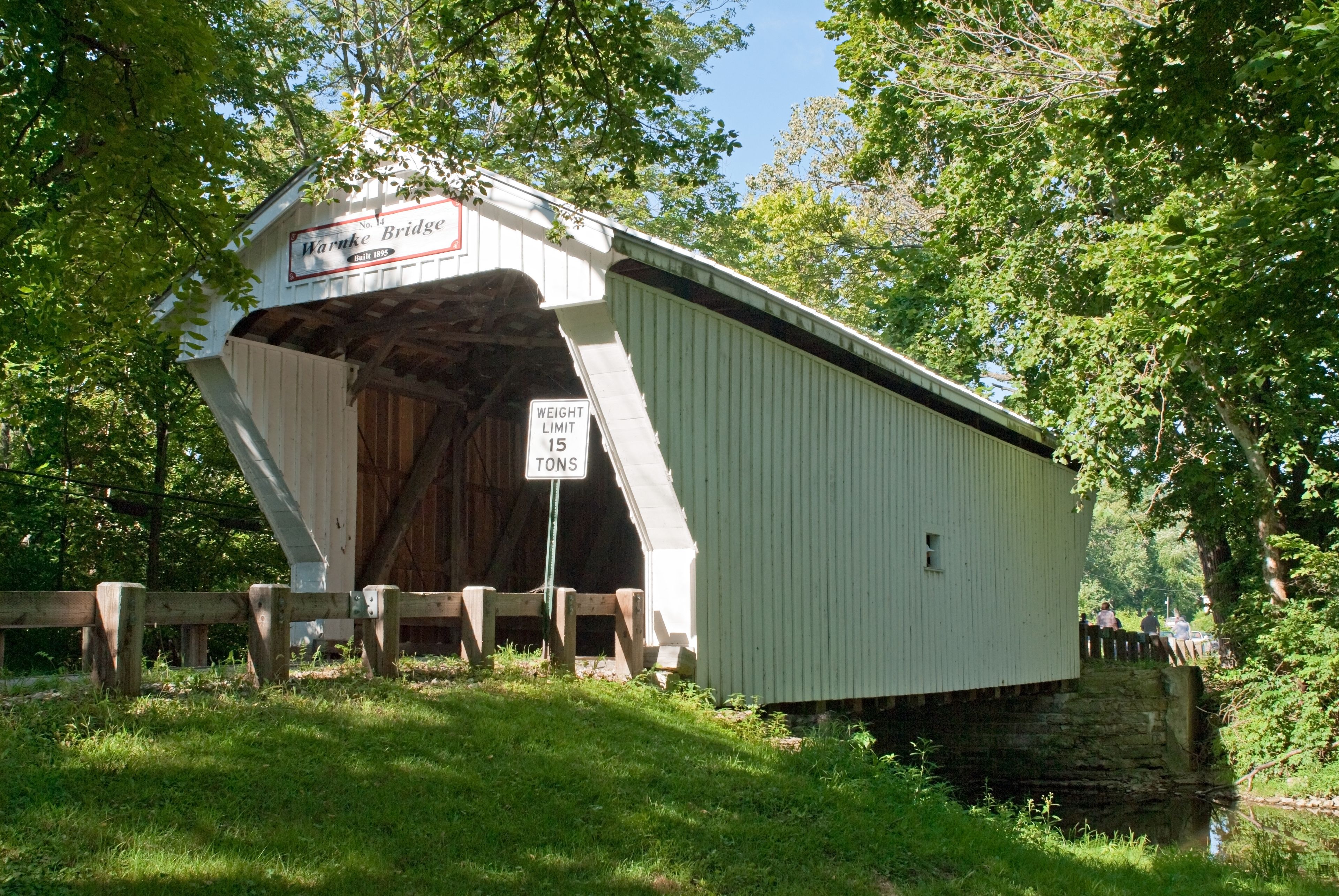 A covered bridge with a sign indicating a weight limit of 15 tons.