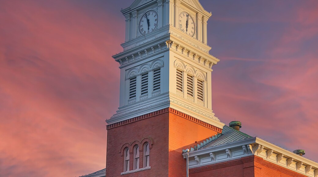 A historic building with a clock tower, red brick facade, and a flagpole with the American flag.