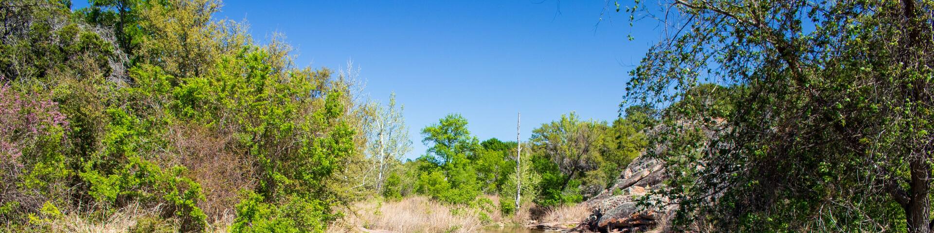 Spring creek a small tributary of water in a valley located at Inks Lake State Park in Burnet County many people visit this park for camping, hiking and fishing