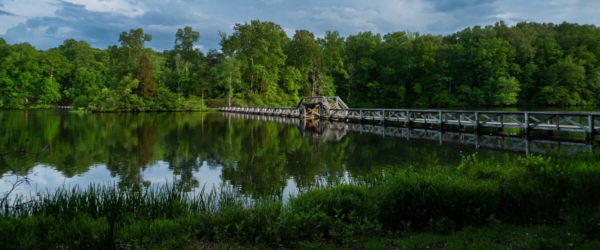 Foot bridge over the lake with reflections, stormy sky
