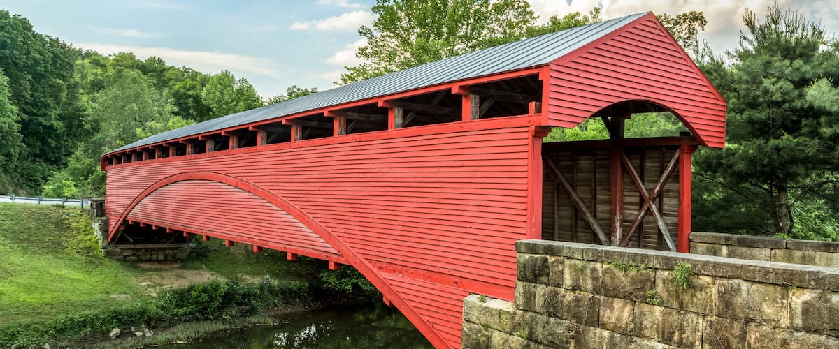 Built in 1853, the historic red Barrackville Covered Bridge crosses Buffalo Creek in Marion County, West Virginia not far from the city of Fairmont.