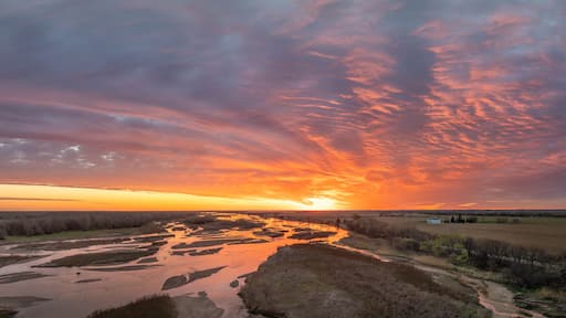 Een rivier bij zonsondergang onder een bewolkte lucht.