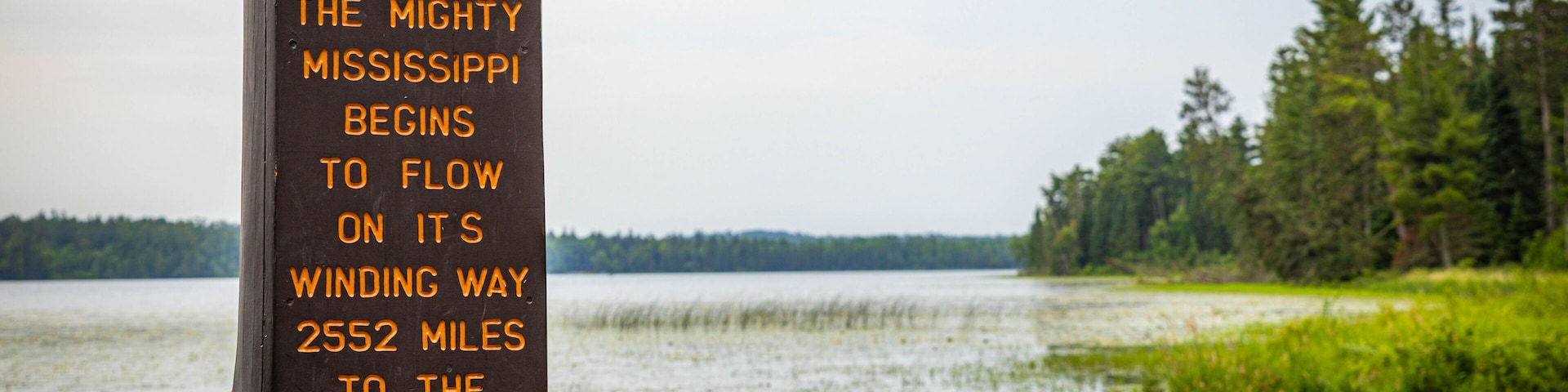 A sign by a lake with text about the Mississippi River's flow.