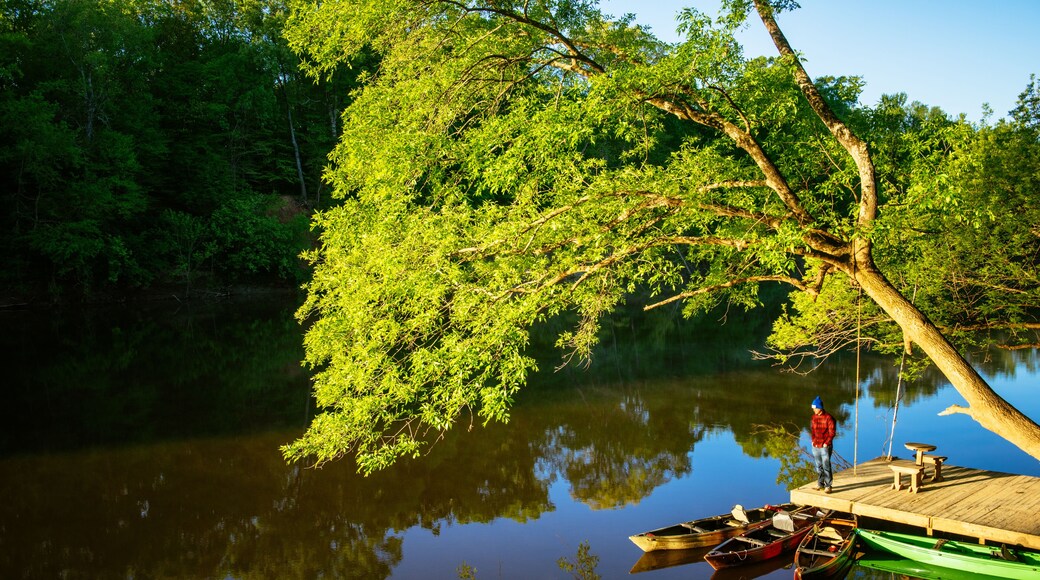 A man in a red jacket stands on a boat dock in the sun along the cape fear river in north carolina