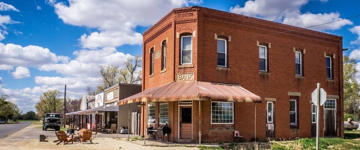 A red brick bank with a sign, a covered porch, and a parked truck.