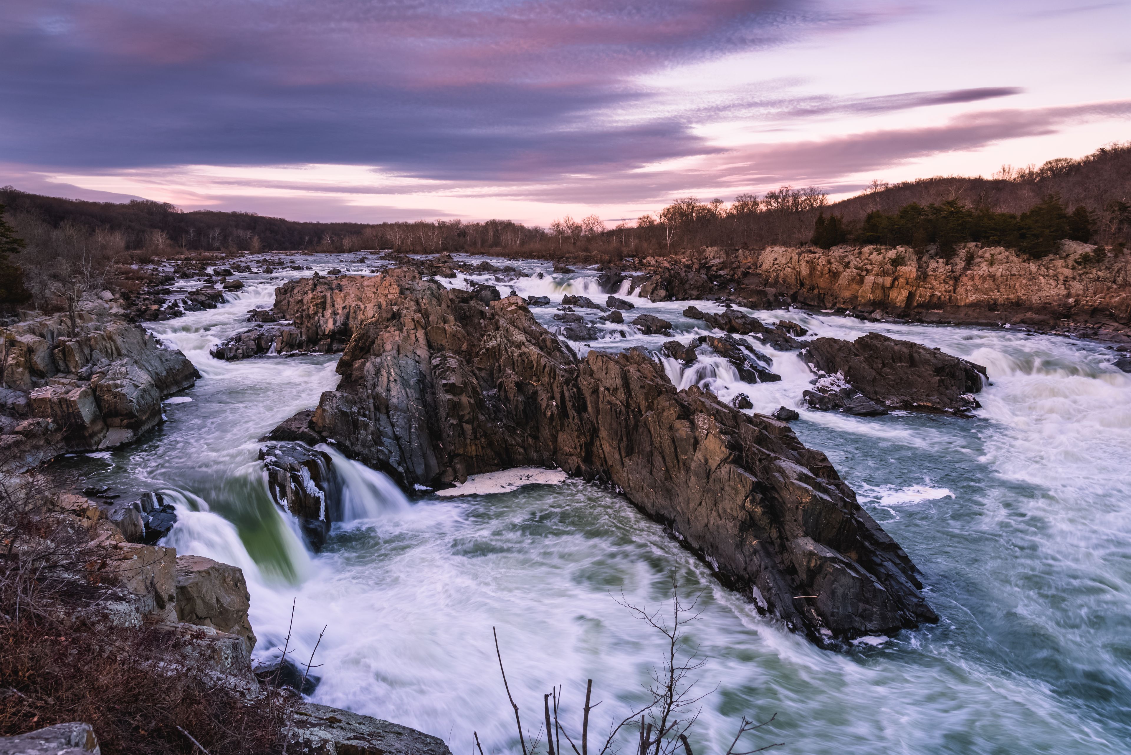A river with a waterfall, surrounded by rocky terrain and trees.