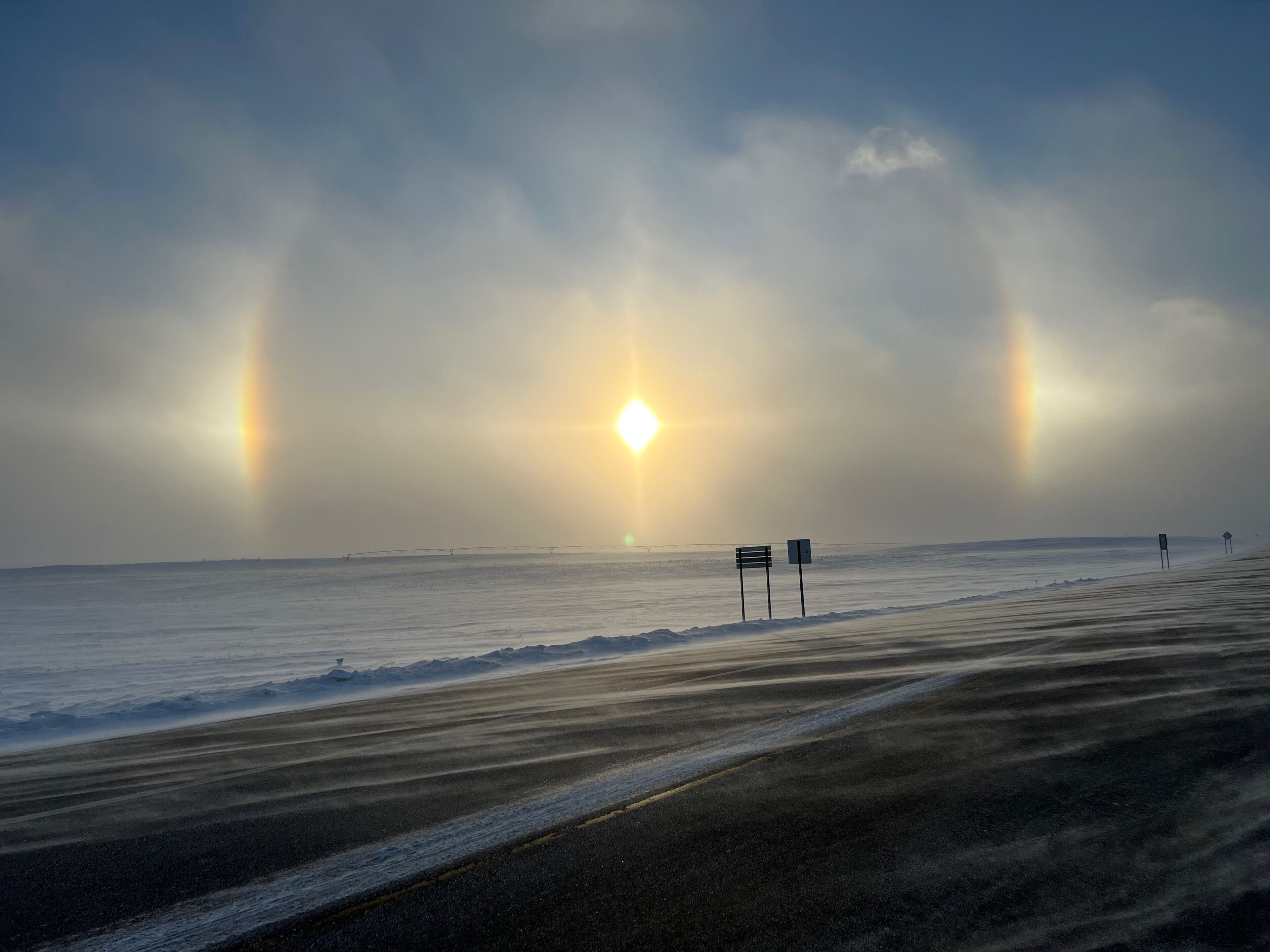 Winter sun dogs across frozen rural fields and road