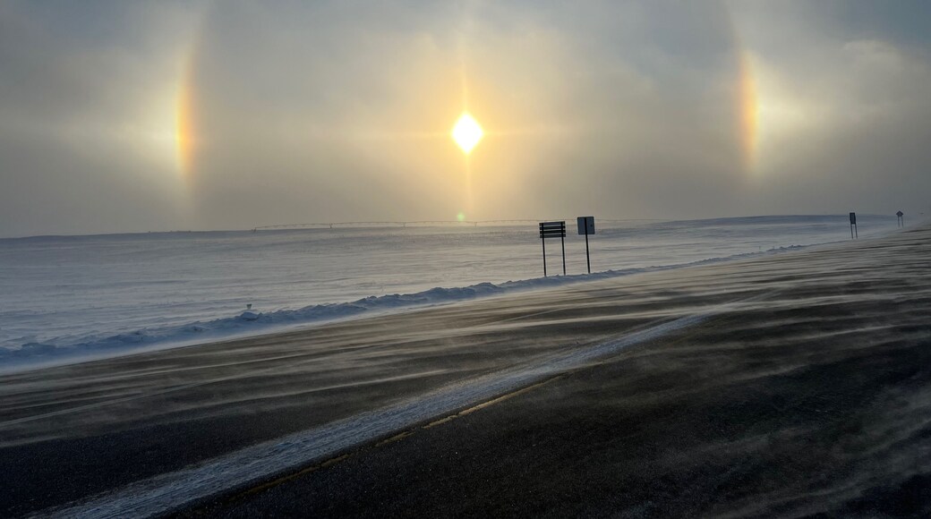 Winter sun dogs across frozen rural fields and road