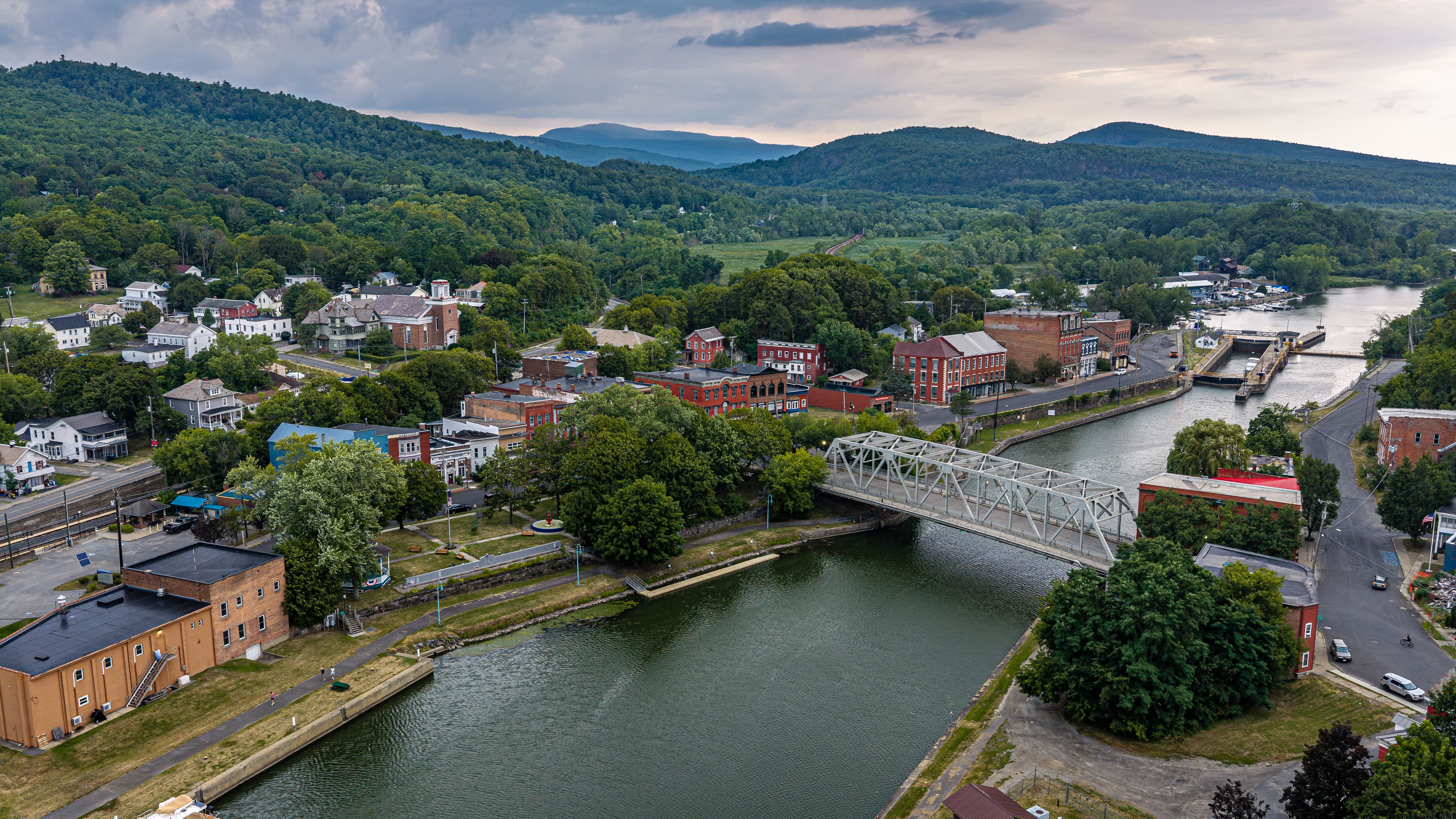 A river with a bridge, a town with historic buildings, and a mountainous backdrop.