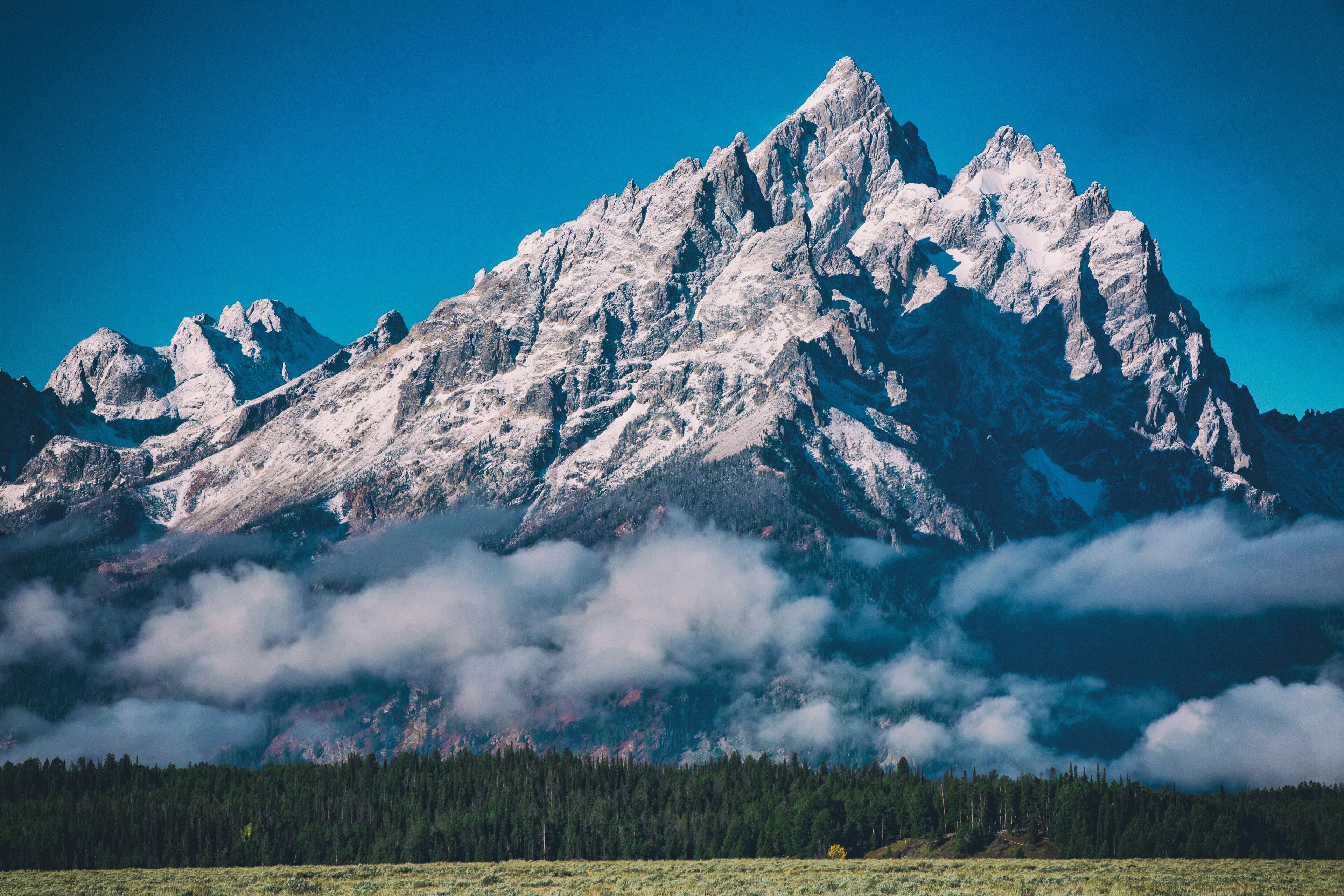 A snow-capped mountain peak with a forested valley below.