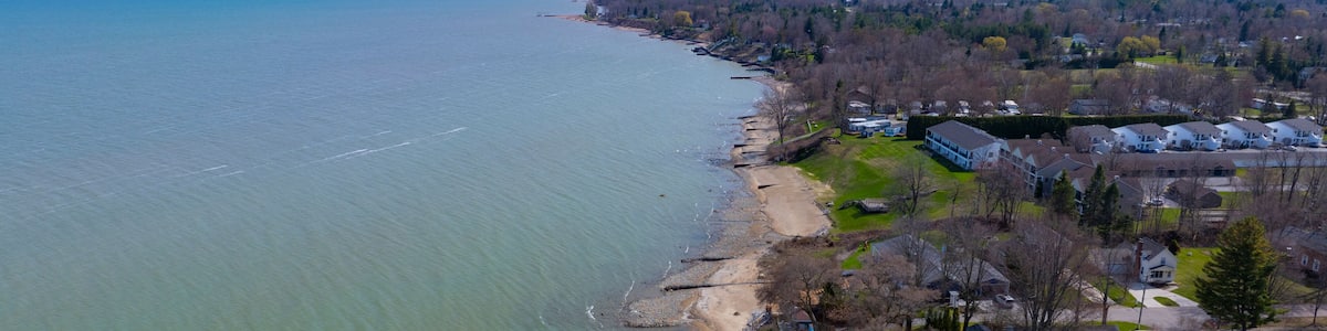 A coastal town with a sandy beach, residential houses, and a view of the ocean.