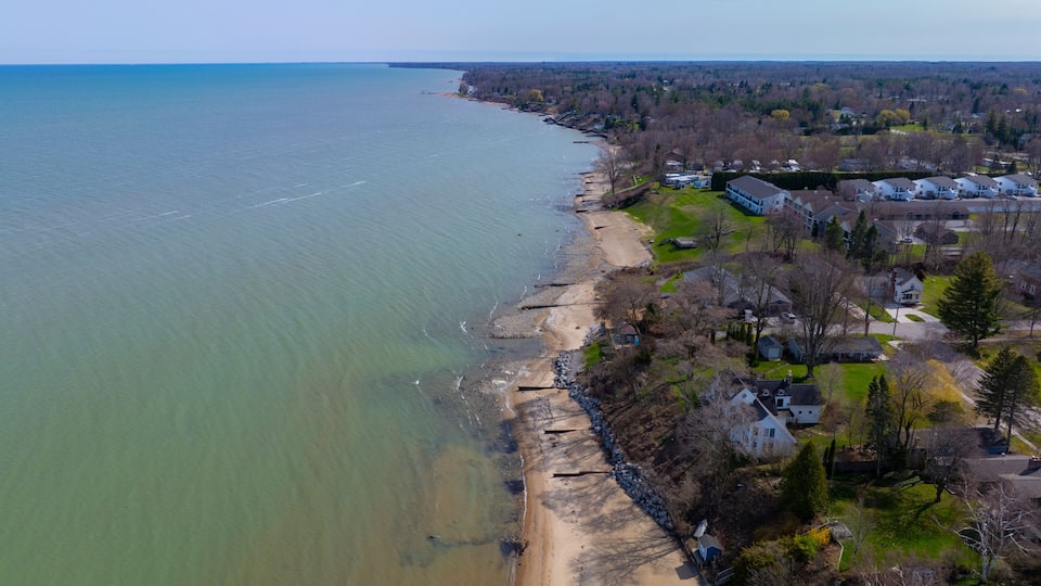 A coastal town with a sandy beach, residential houses, and a view of the ocean.